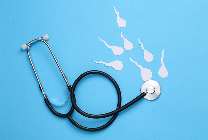 A stethoscope lays against a blue surface with white sperm swimming towards the chest piece.