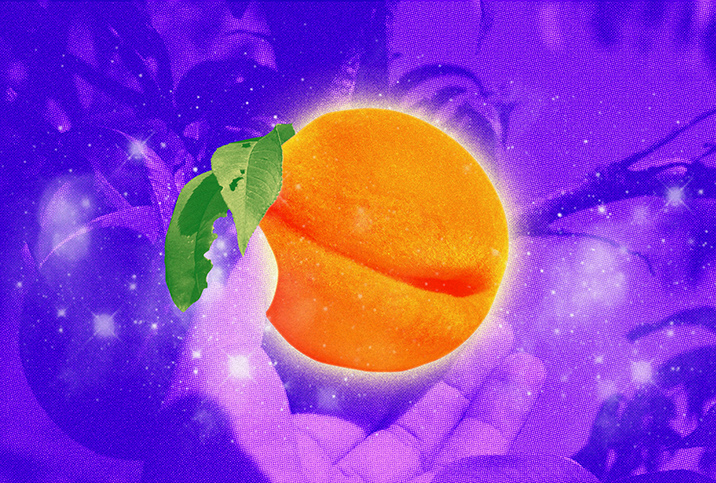A purple tinted hand holds a brightly glowing orange peach. 