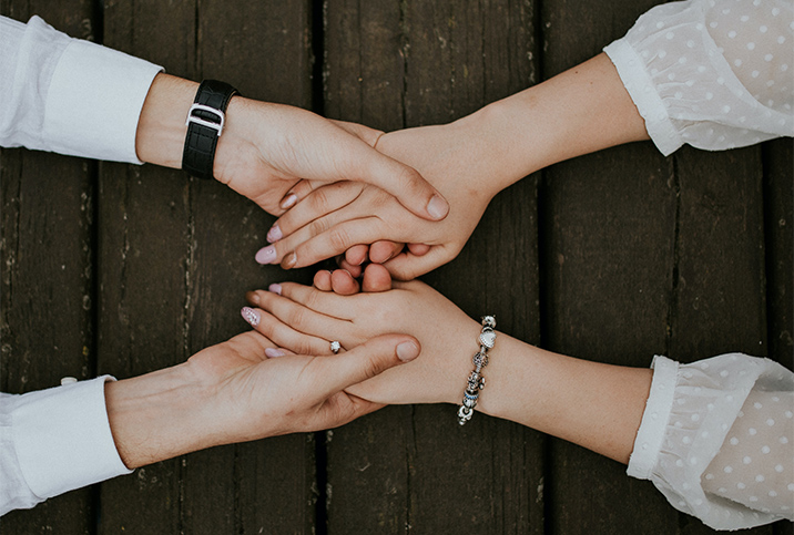 A man and woman hold hands across a wooden table.