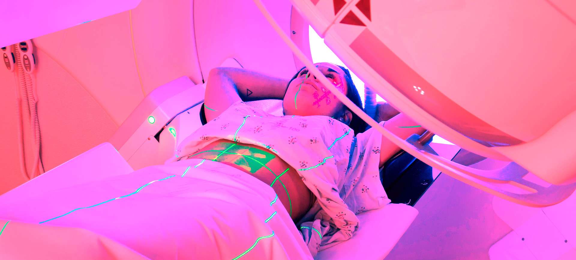 A woman lies down under a radiation machine.