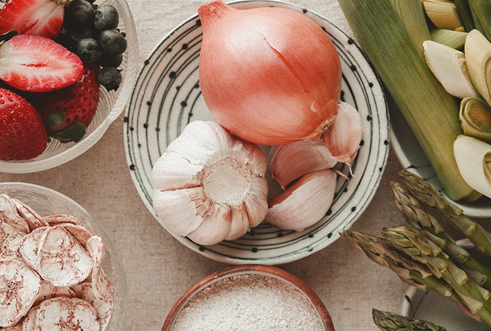 A view from above shows fruits and vegetables sit in bowls on a table.