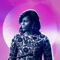 Michelle Obama stands in front of a microphone looking to her right with a fuchsia and white background.