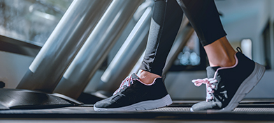 A person is walking on a treadmill with only their lower legs and feet showing.