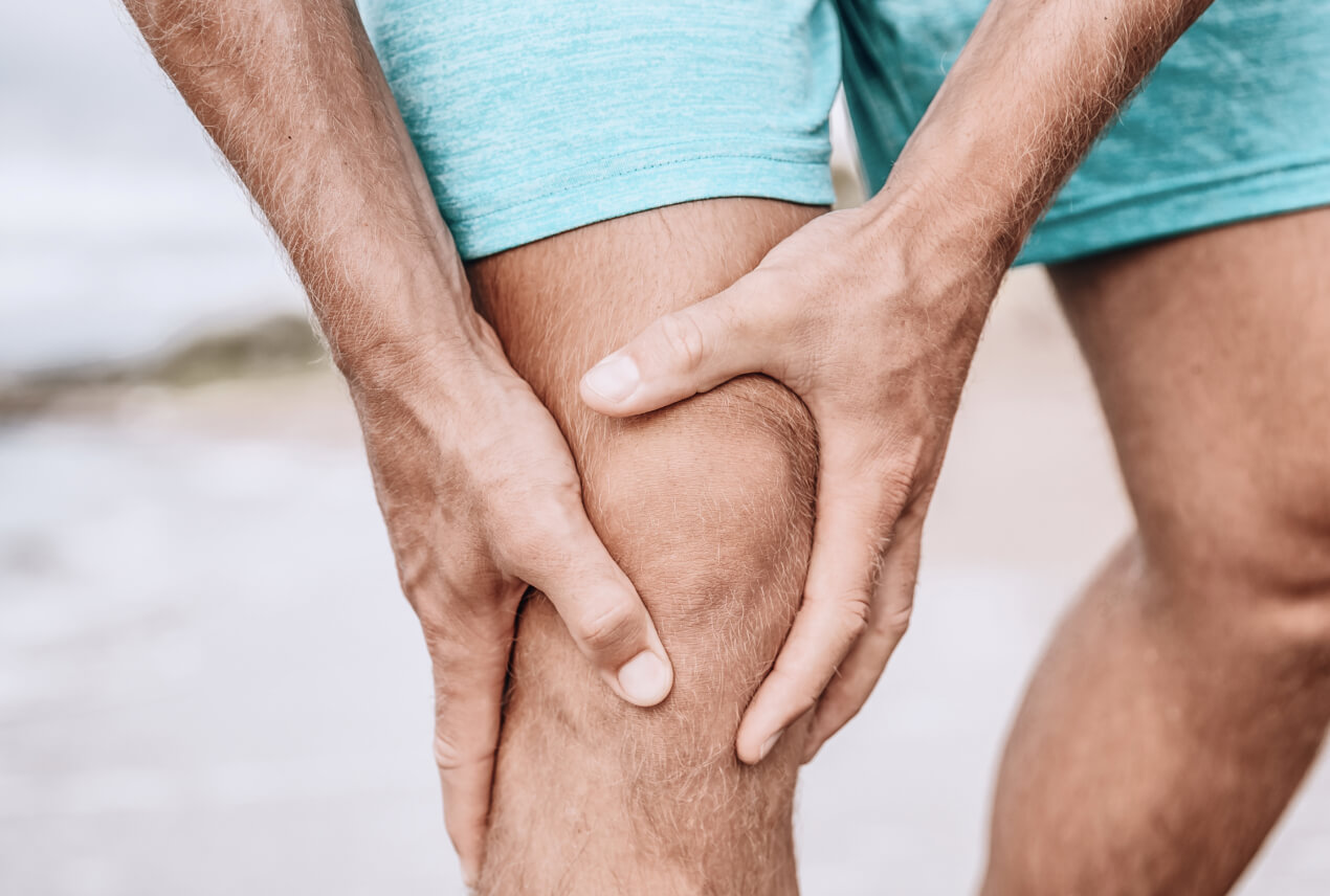 A person holds their knee in pain with both hands.
