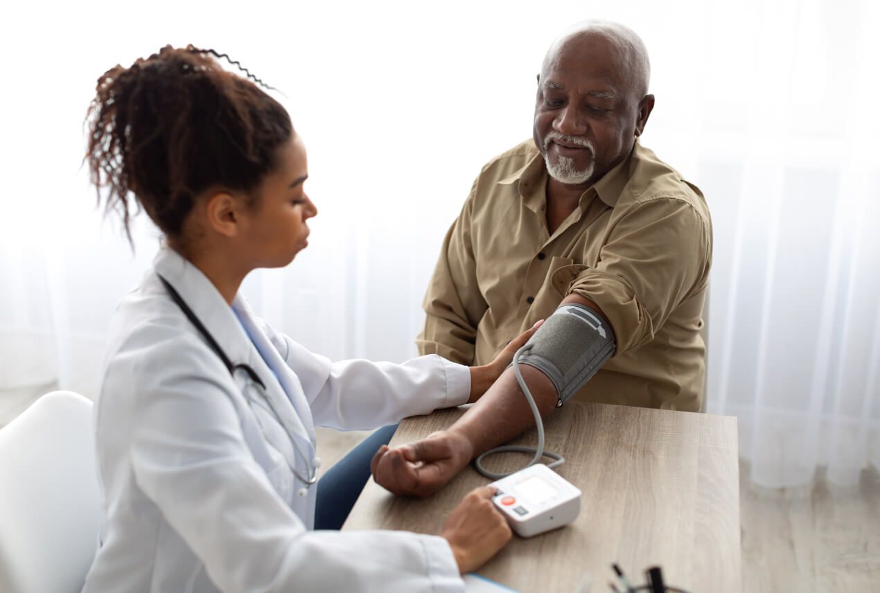 A female doctor checks a man for high blood pressure.