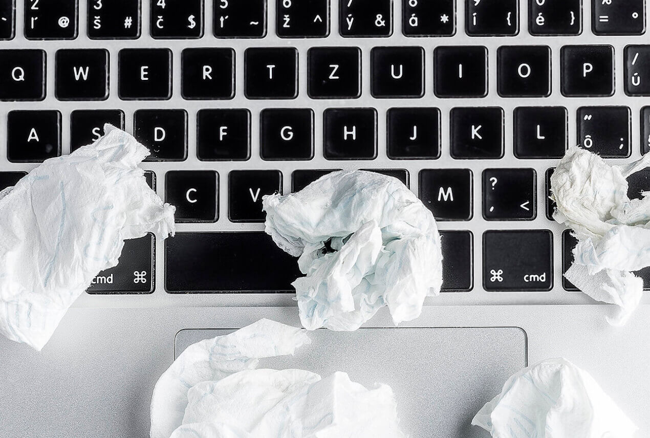 Wadded up tissues lay against a laptop keyboard.