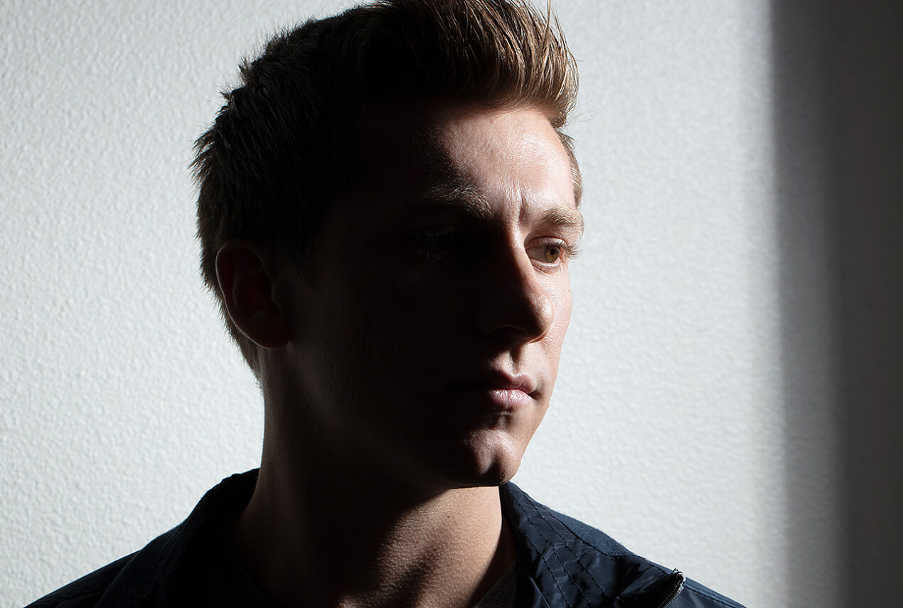 A man looks to the side and half his face is shadowed.
