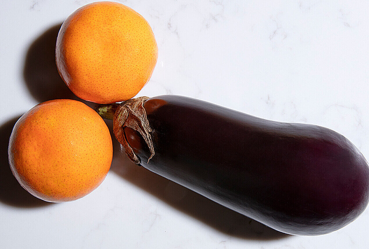 An eggplant is placed adjacent to two oranges like penis and testicles.