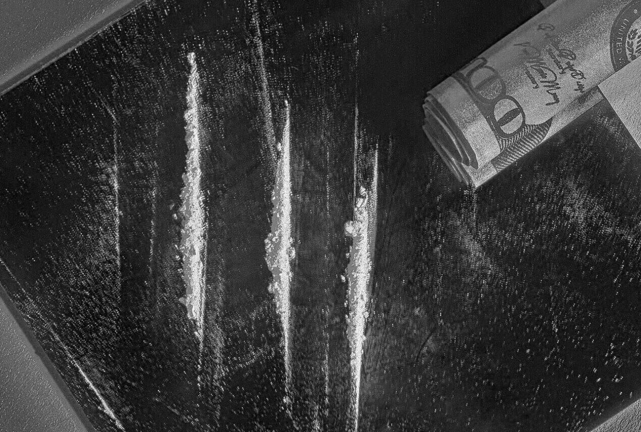 A rolled bill hovers over three lines of cocaine.