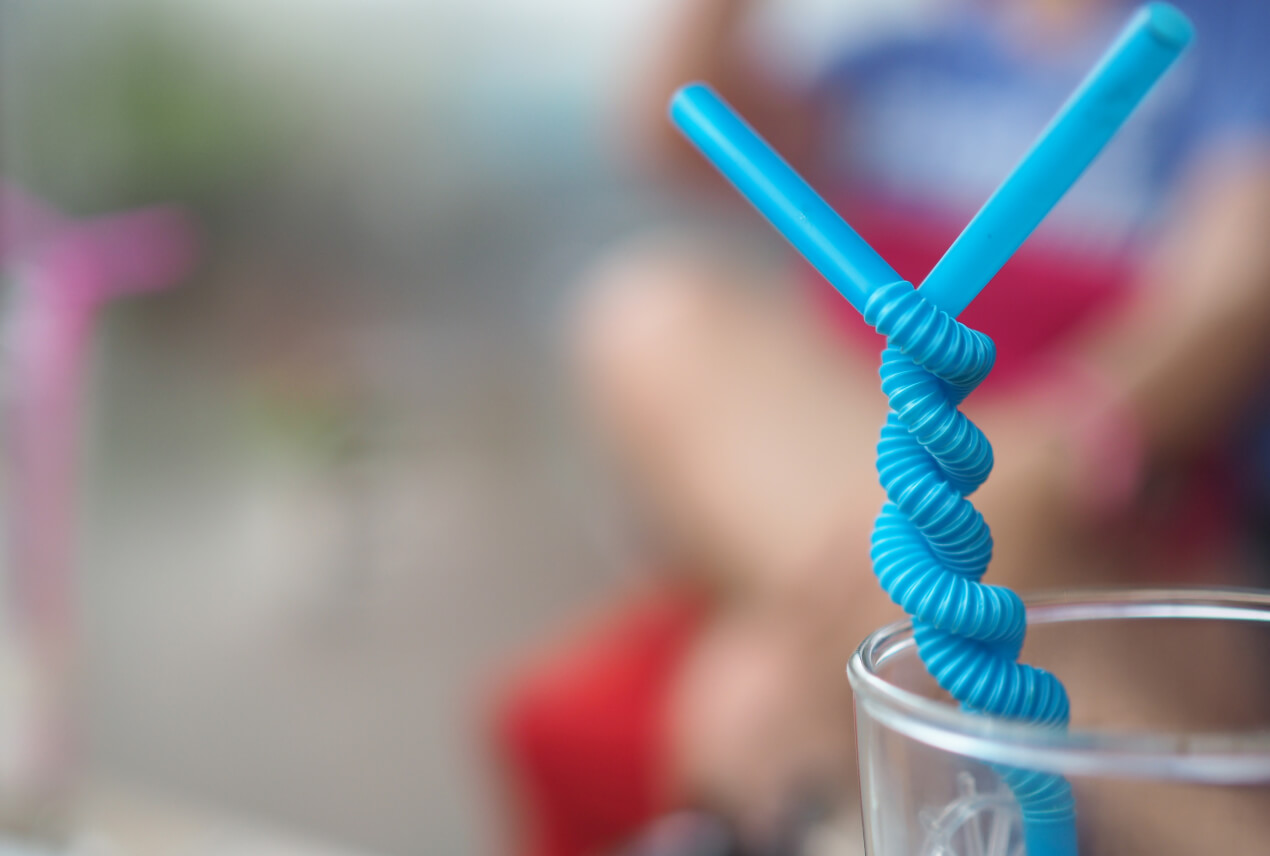 Two blue straws twist around each other in a glass.