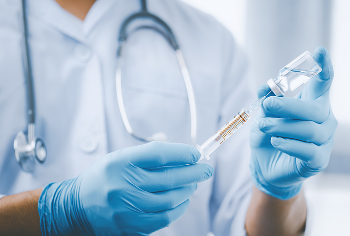 A gloved doctor holds a needle in their hands. 