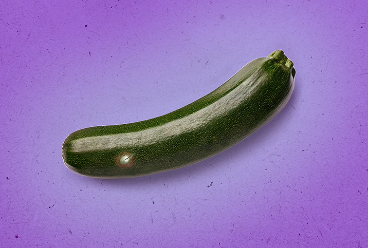 A cucumber with an ingrown hair lays against a purple surface.