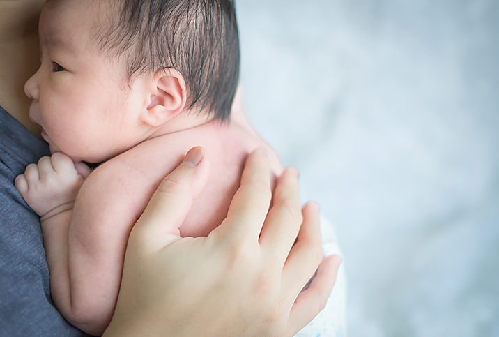 A parent holds their baby against their chest.