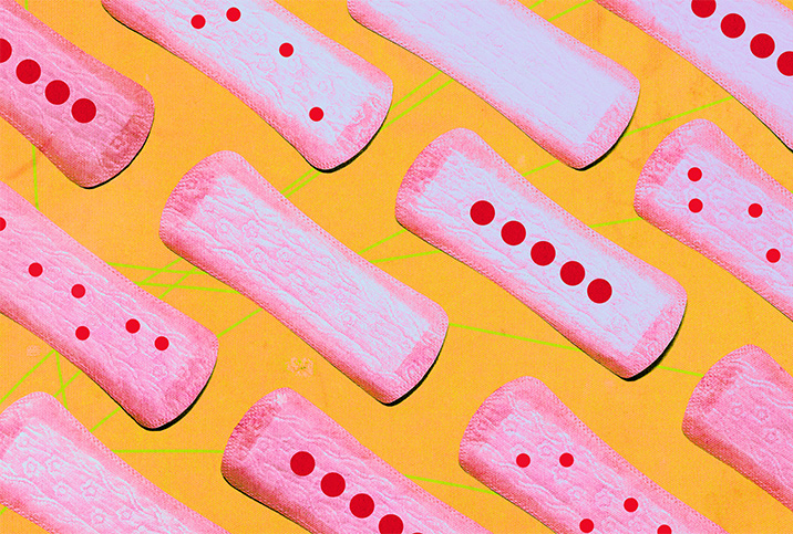 Pink menstrual pads lie opened, next to one another, with red dots on some.