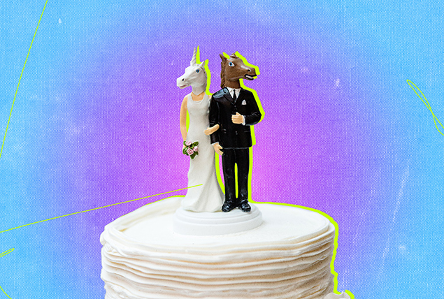 A wedding cake topper has a unicorn head and a horse head atop the bodies.