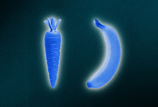 A carrot and a banana are side-by-side and lit in blue against a dark green background.