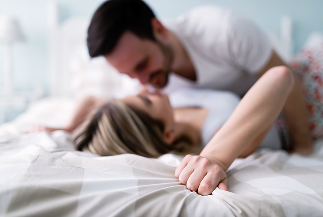 A man lays on top of a woman in bed.