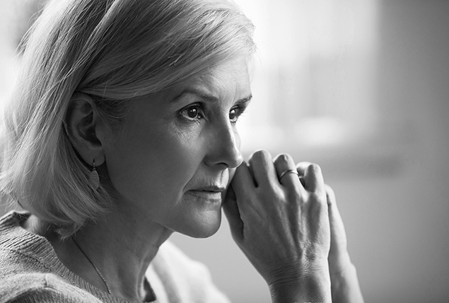 A black and white photo shows a woman with white hair looking into the distance.