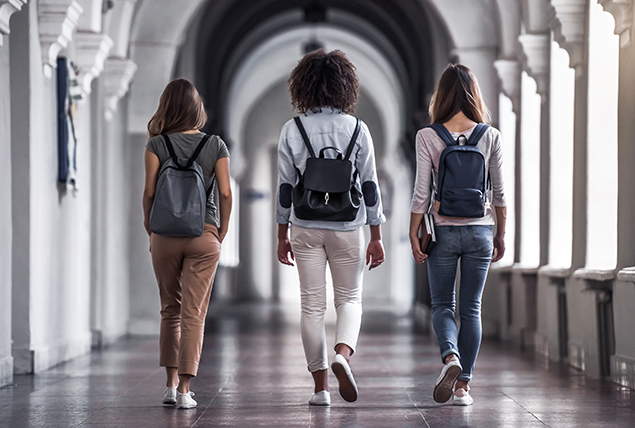 Three college students walk down a hallway.