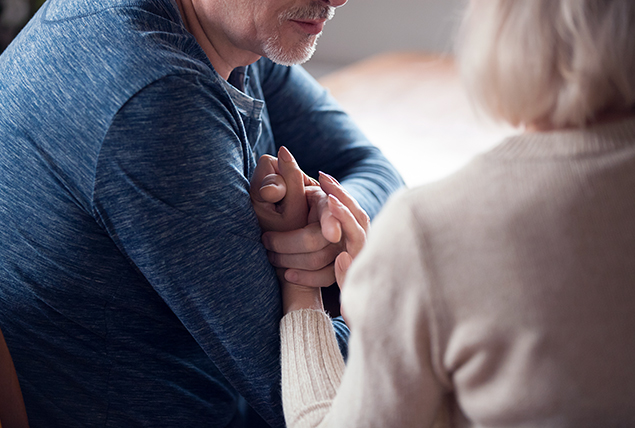 A senior man holds the hand of a senior woman.