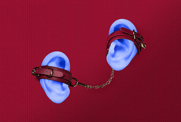 A pair of leather handcuffs are attacked to two light blue ears against a red background.