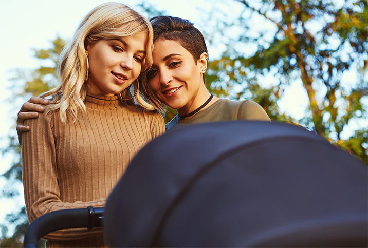 A lesbian couple looks down at a stroller.