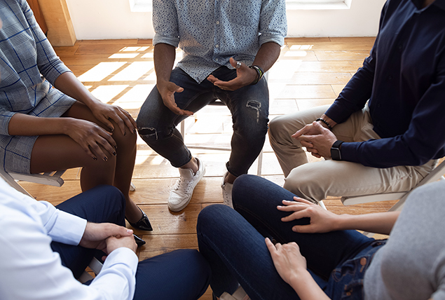 A group of people sit in a circle during therapy.