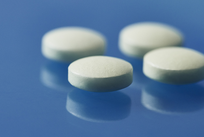 Four aspirin pills lay along a glassy blue surface.