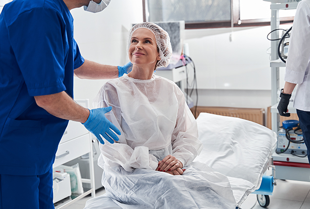 A woman sits on a hospital bed before undergoing a colonoscopy.