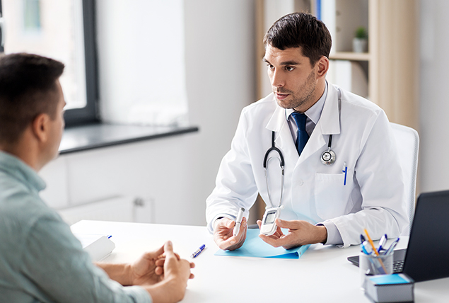 A doctor sits at a table explaining diabetes symptoms to a man on the other side.