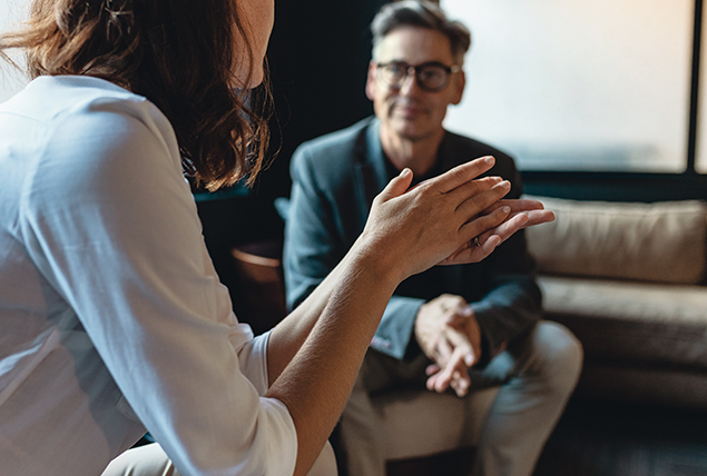 A man and woman sit in a living room discussion vasectomies.