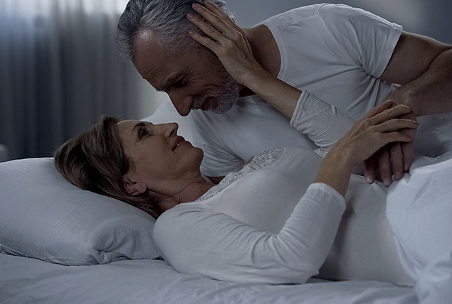 A senior couple embraces in bed.