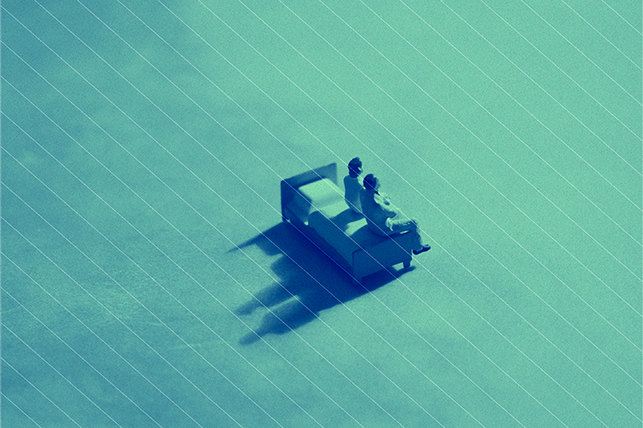 Two figures sit on a bed with a green light shining down on them.