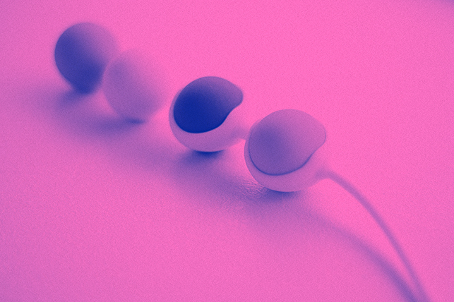 A pair of kegel balls lay on a pink surface.