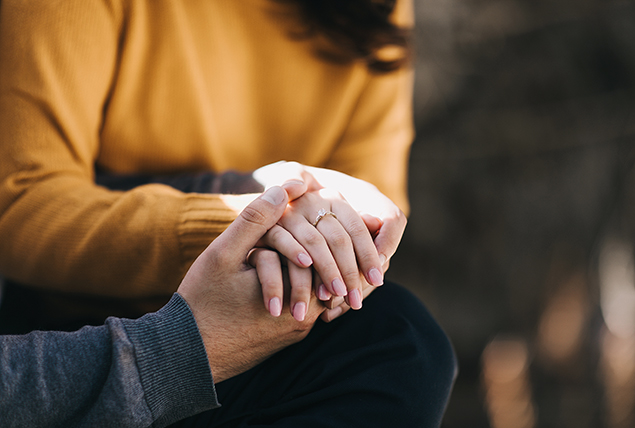 A man holds the hand of a woman who has has a miscarriage.