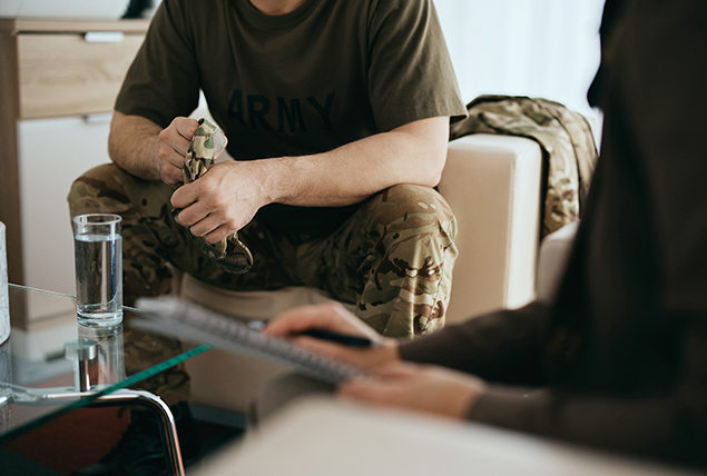 A veteran sits in a chair gripping his hat as he listens to a doctor talk about his prostate care options.