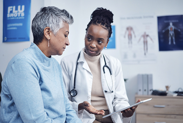 woman speaks i a doctors office with a doctor in a white coat