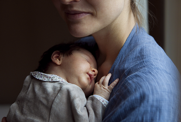 A woman holds a newborn baby.