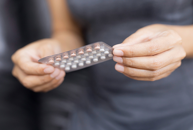 A woman with endometriosis holds a packet of pills.
