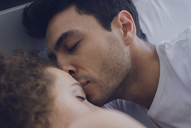 a man and a woman cuddle as he kisses her forehead