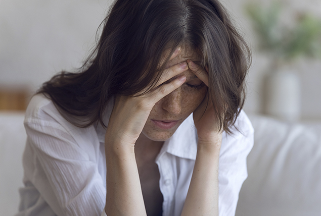 a woman hangs her head in her hands in pain