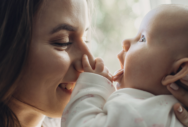 a woman smiles as her baby touches her face