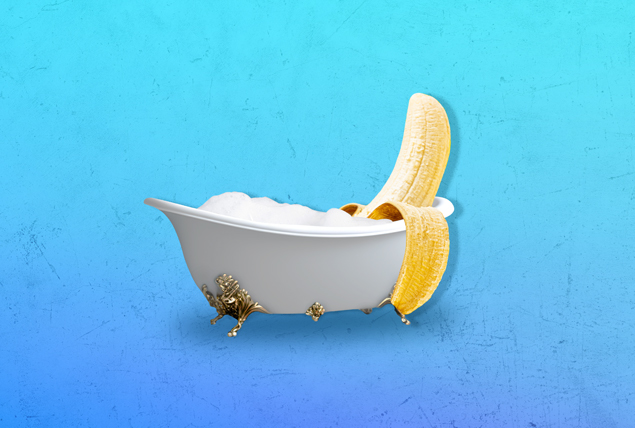 a banana sits in a claw foot bathtub on a blue background