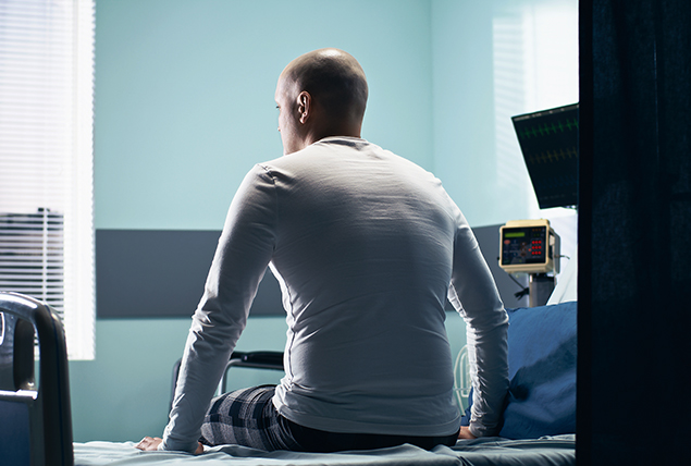 man in a white shirt sits on a doctors office bed