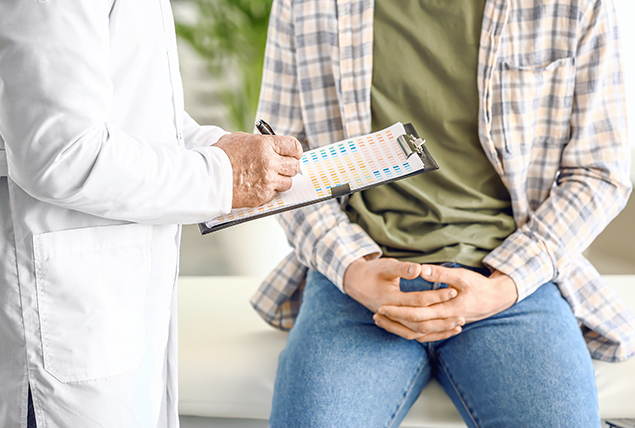 person with hands in lap sits on doctor's table facing doctor in white coat holding clipboard