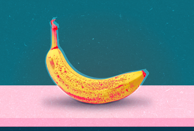banana with red splotches on pink surface with teal background