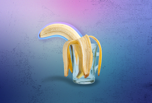banana turned downward in clear glass on blue and pink marbled background