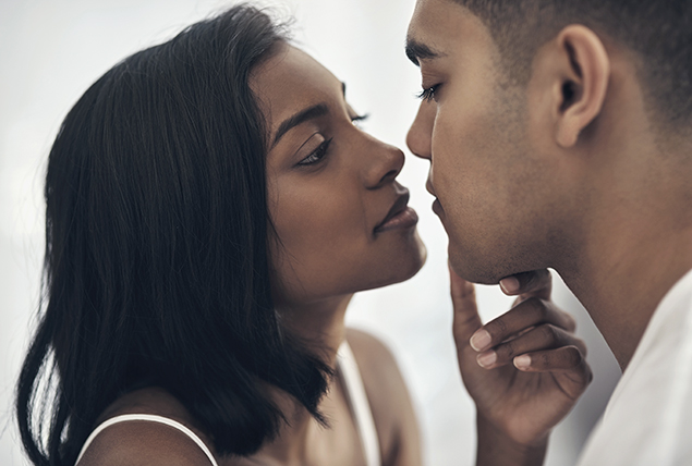 woman holds the face of a man as they are about to kiss