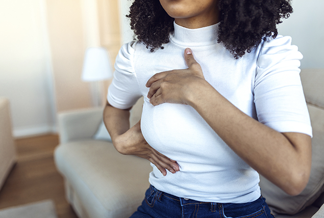 woman in white shirt touches her breast giving a self exam