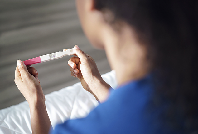 person in blue shirt sits and holds negative pregnancy test